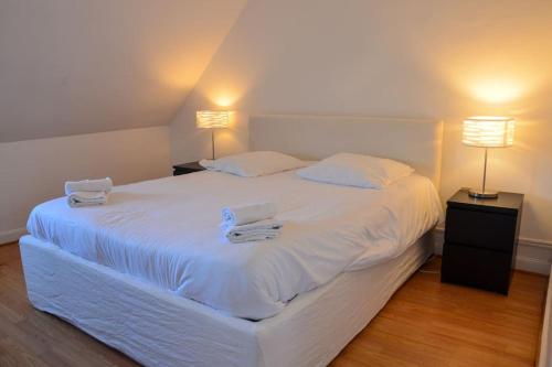 une chambre avec un grand lit blanc avec deux serviettes dessus dans l'établissement Camelia; Beau logement lumineux, avec vue sur mer, à Wimereux