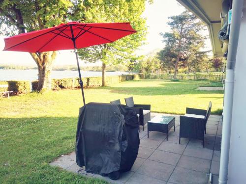 un parapluie rouge assis à côté d'une table et de chaises dans l'établissement La Bordu, à Grandson