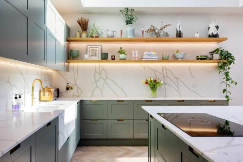 a kitchen with green cabinets and white counter tops at Veeve - A Symphony in Green in London