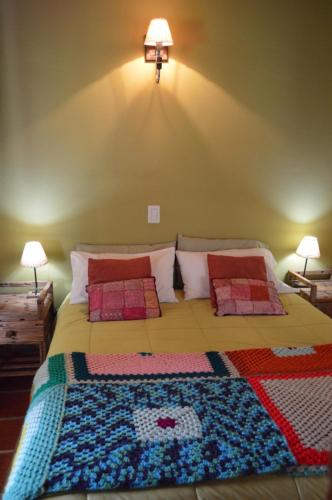 a bedroom with a bed with a colorful blanket on it at Complejo Dulcería El Cazador y cabañas in Tandil