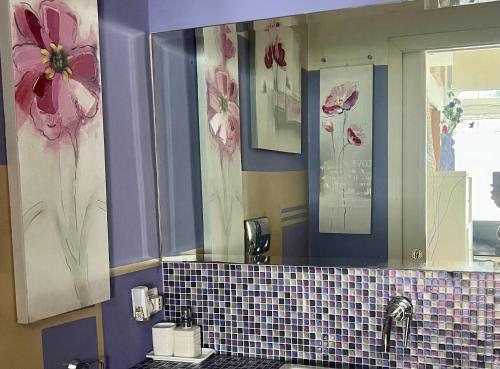 a bathroom with a sink and a mirror with flowers on the wall at Camilluccia in Rome