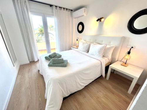 a white bedroom with a white bed and a window at El Paraiso in Alcudia