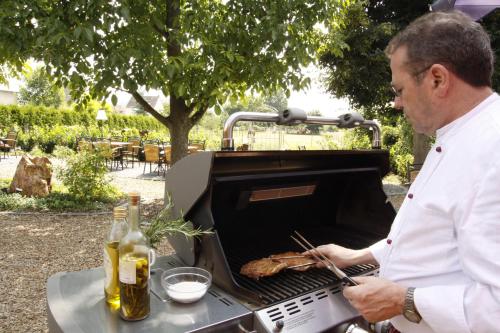 a man cooking a steak on a grill at Fetzers Landhotel in Ingelheim am Rhein