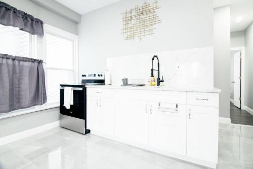 een keuken met witte kasten en een zwart apparaat bij Modern 1 Bedroom Apartment close Falls and Casino in Niagara Falls