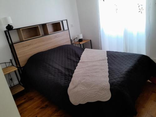 1 dormitorio con 1 cama con manta blanca y negra en bel appartement en Combronde