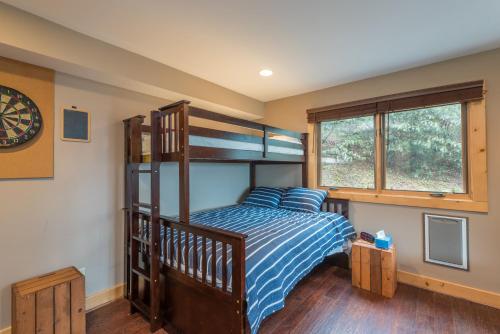 a bedroom with a bunk bed with a blue striped bedspread at Blue Ridge Bliss Gorgeous home with hot tub & stunning views in Weaverville