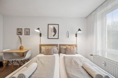 2 Betten in einem Schlafzimmer mit einem Schreibtisch und einem Fenster in der Unterkunft Sali-Bayreuth SB19 Komfortable Wohnung in der Nähe des Zentrums in Bayreuth
