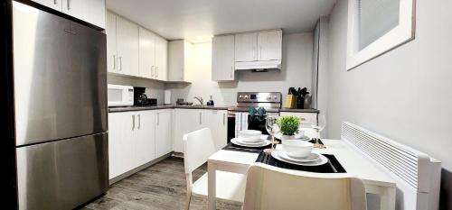 a kitchen with white cabinets and a table and chairs at Guest Suite in Saint Hubert, bus to REM and Metro in Longueuil