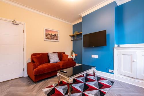 a living room with a red couch and a tv at 2 Bedroom House in the Heart of Leicester in Leicester