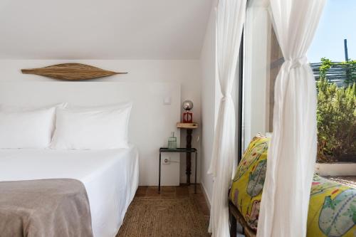 a white bedroom with a bed and a window at Altanure Almatere - Food Forest Boutique Stay in Tavira