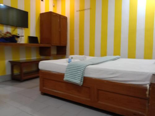 uma cama num quarto com riscas amarelas e brancas em HOTEL SOWMYA INN em Ongole