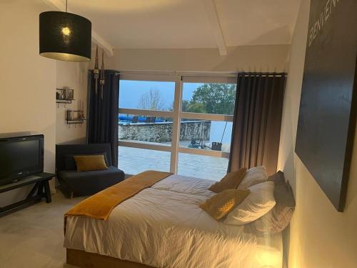 a bedroom with a bed and a large window at La Maison Culier in Sainte-Alauzie