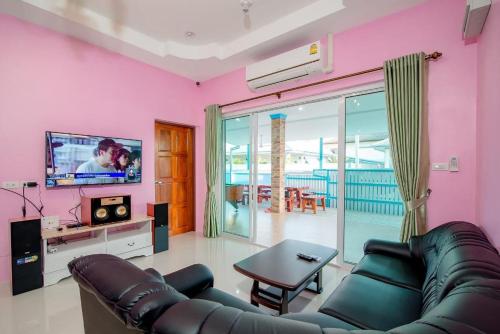 a living room with a couch and a flat screen tv at Blue house pool villa in Cha Am
