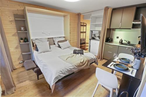 1 Schlafzimmer mit einem großen Bett und einer Küche in der Unterkunft Magnifique studio avec terrasse au centre in Crans-Montana