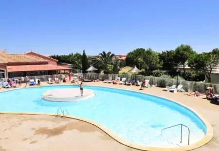 une grande piscine au milieu d'un complexe dans l'établissement Agréable maisonnette piscine collective 4IDP3031, au Barcarès
