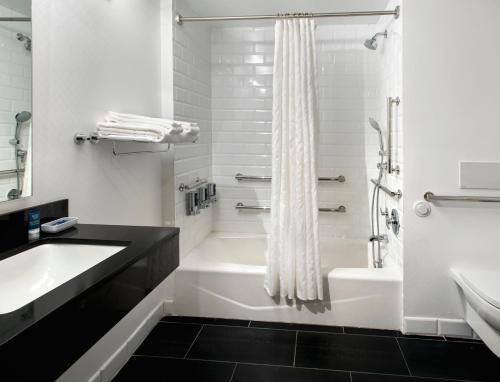 een witte badkamer met een bad, een wastafel en een douche bij Four Points by Sheraton Manhattan SoHo Village in New York