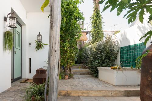 a courtyard with stairs and plants and a green door at Altanure Almatere - Food Forest Boutique Stay in Tavira