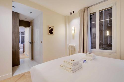 um quarto com uma cama branca e toalhas em Brand New Home in the Heart of Latin Quarter em Paris