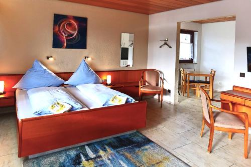 a bedroom with a bed with blue pillows and a desk at Hotel Garni Sebastian in Kirrweiler