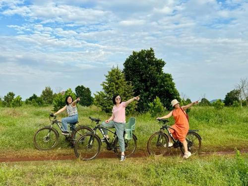three people on bikes with their arms out in a field at Tropical eglamping in Tân Phú
