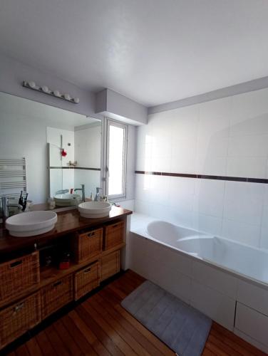 une salle de bain avec deux lavabos, une baignoire et un miroir dans l'établissement La canopée : séjour alliant culture, nature, sport, à Nantes