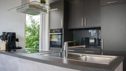 a kitchen with a stainless steel sink and black cabinets at Gartenwohnung mit Alpenblick in Fritzens