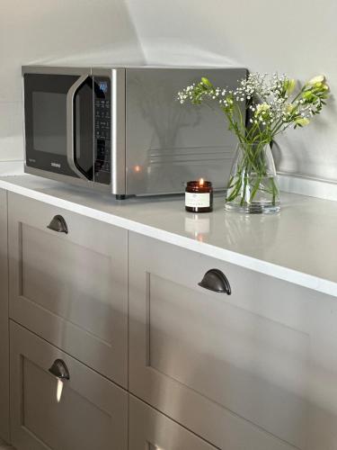 a microwave on a counter with a vase of flowers at Central Warwick, Free Parking and Roof Terrace in Warwick