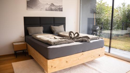 1 cama con marco de madera en una habitación con ventana en Gartenwohnung mit Alpenblick, en Fritzens