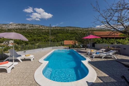 a swimming pool with chairs and an umbrella at Villa Almond near Omis, private pool in Tugare