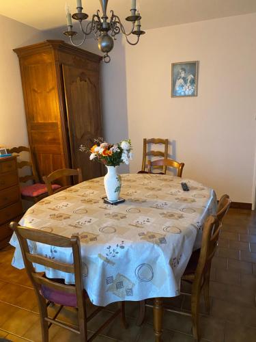 une table de salle à manger avec un vase de fleurs dessus dans l'établissement Maison de famille proche Futuroscope, à Châtellerault
