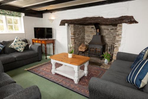a living room with a table and a fireplace at The Old Farmhouse in Liskeard