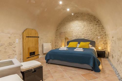 a bedroom with a bed in a stone wall at Le Troglogite Mignon - Maison et Jardin in Amboise