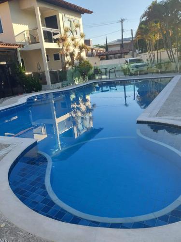 une grande piscine avec des carreaux bleus en face d'un bâtiment dans l'établissement Villa Saudade, à Porto Seguro