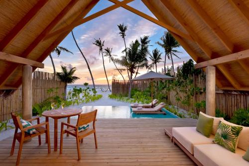 a wooden deck with a table and chairs and a pool at Fushifaru Maldives with 50 percent off on sea plane roundtrip 04 nights & above in Fushifaru