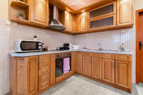 a kitchen with wooden cabinets and a microwave at Просторна вила с впечатляващ изглед в централен Балкан in Kravenik