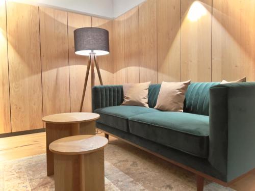 a living room with a green couch and a lamp at Aclavaldafur Apart in Nauders