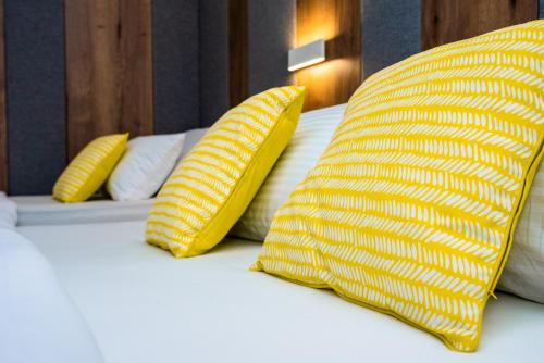 a bed with two yellow pillows on it at Swiss Plus Hotel in Bihać