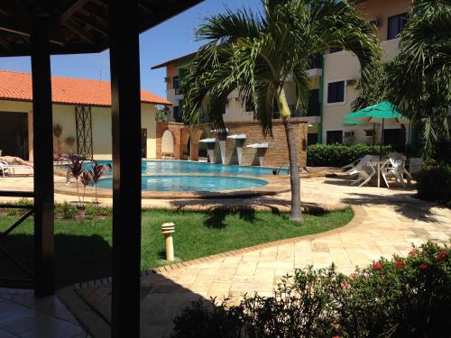 a swimming pool in a resort with a palm tree at Vilamar Suítes in Aquiraz