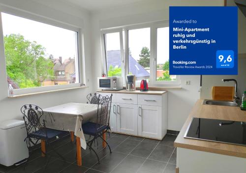 a kitchen with a table and chairs and windows at Mini-Apartment ruhig und verkehrsgünstig in Berlin in Berlin