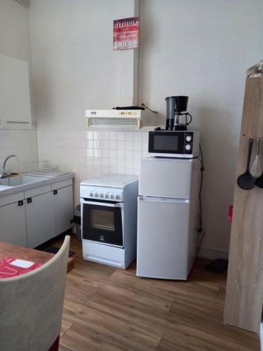 une cuisine avec une cuisinière et un micro-ondes dans l'établissement F1 Rez De Chausée, à Néris-les-Bains