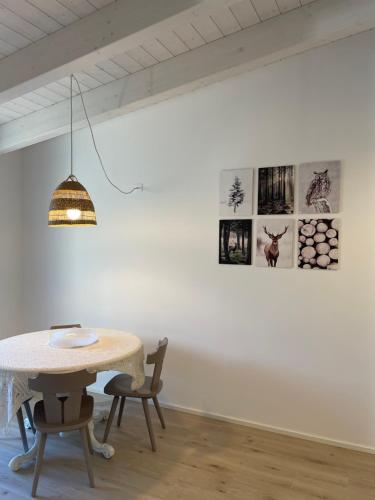 een tafel en stoelen in een witte kamer met foto's aan de muur bij Appartamento Ginepro in Pian dei Pradi