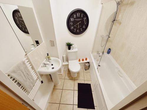a bathroom with a toilet and a clock on the wall at 2 Bed Apartment Sleeps 6 Modern Secure Parking + Lift in Newcastle upon Tyne