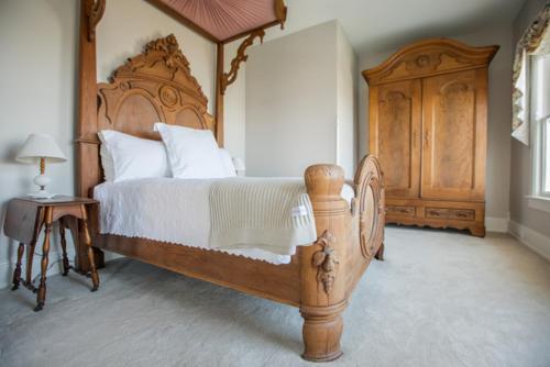 a bedroom with a large wooden bed and a wooden dresser at Clifton House - Panorama - Queen Suite, Sleeps 4, River Views in Natchez