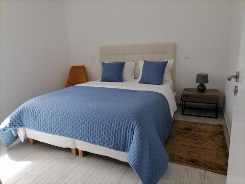 a bedroom with a large bed with blue pillows at Casa Fraga do Suadouro in Campo do Gerês