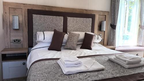 a bedroom with a large bed with towels on it at Binka - Luxury 40 x 14ft Lodge in Tain