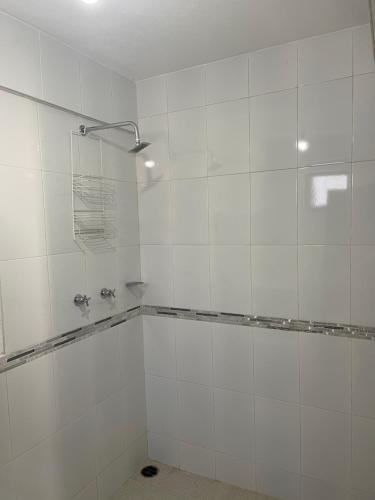 a white tiled bathroom with a tub and a shower at Departamentos huerta in Taxco de Alarcón