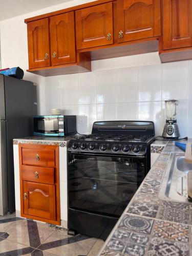 uma cozinha com um fogão preto e armários de madeira em Departamentos huerta em Taxco de Alarcón