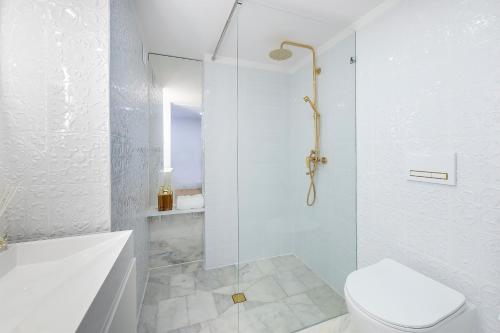 a white bathroom with a shower and a toilet at Piotrkowska 37 - Romantyczna Przystań dla Dwojga in Łódź