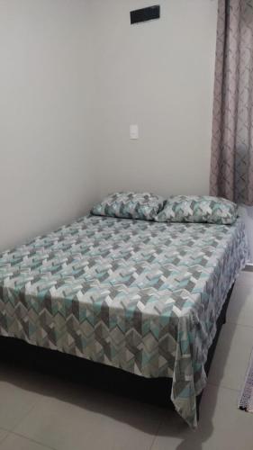 a bed sitting in a room with at Geminado Ibicaré com quarto privativo em casa compartilhada in Joinville