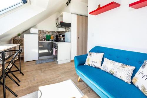 a living room with a blue couch and a kitchen at Appartement Cosy Amiens in Amiens